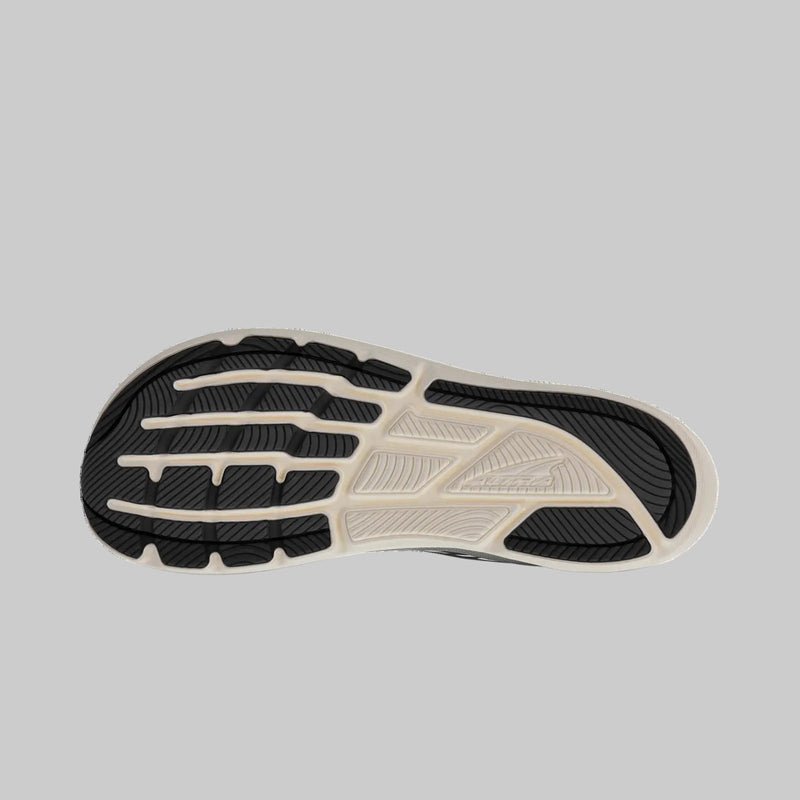 The bottom of a black and white running shoe on a white background