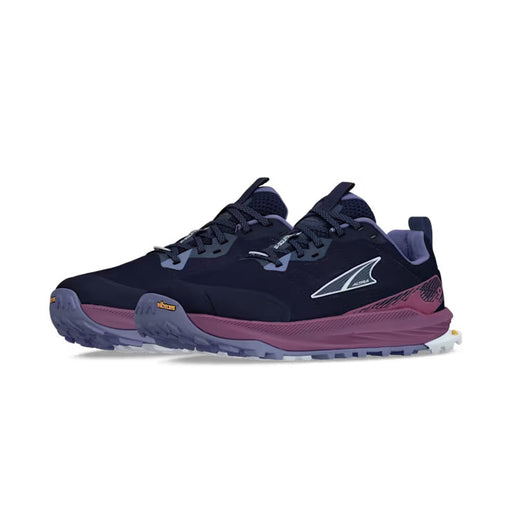 Side view of a pair of navy blue colored trail running shoes with purple accents against a white background. 