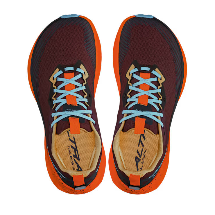 Top view of a pair of red shoes with orange accents and blue laces against a white background. 