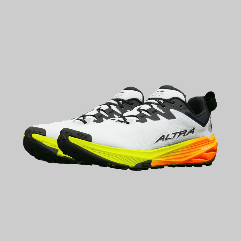 A pair of white running shoes with green and orange bottoms on a white background