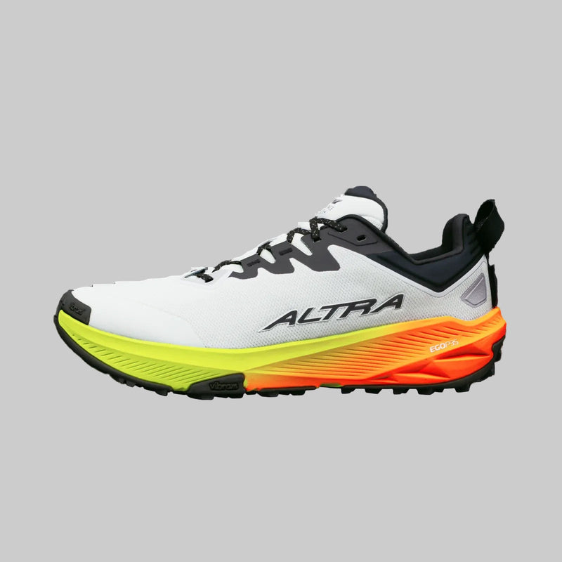 A white running shoe with a green and orange bottom on a white background