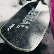 Close up of a black paddle on a white and grey background.
