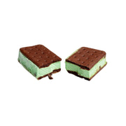 Two ice cream sandwiches with chocolate cookies and green mint cream on a light gray background