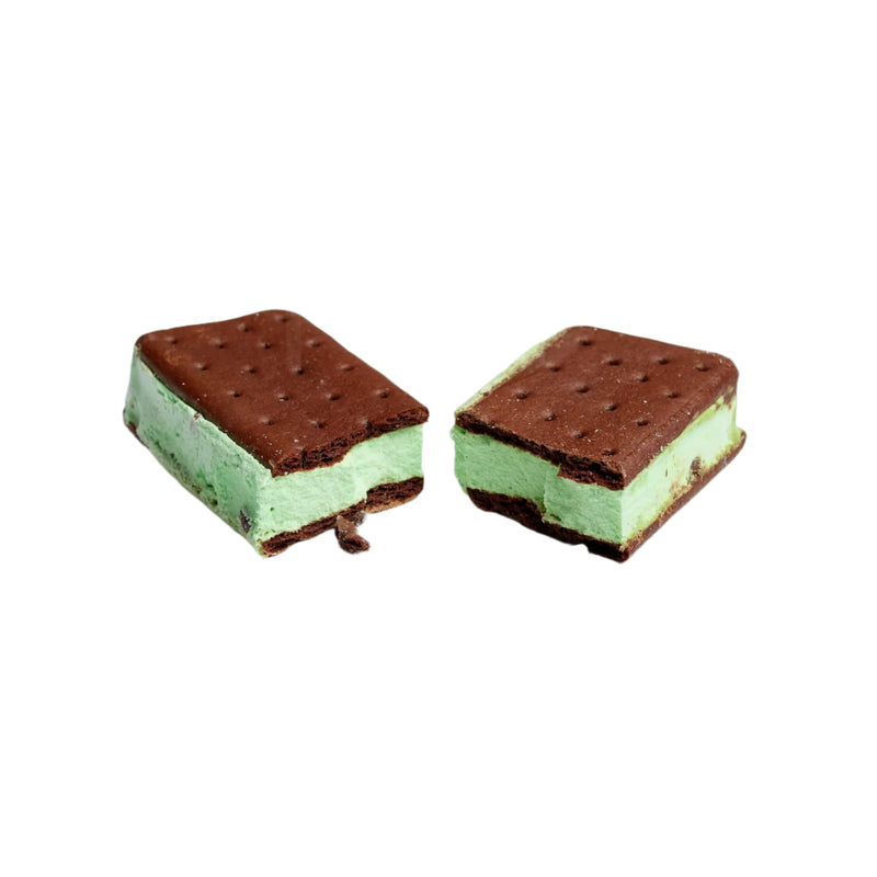 Two ice cream sandwiches with chocolate cookies and green mint cream on a light gray background