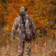 Hunter in camouflage gear with archery equipment in an autumn forest