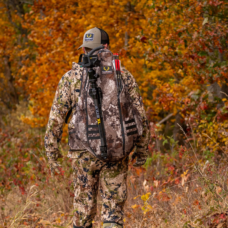 Hunter in camouflage gear with archery equipment in an autumn forest