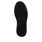 View of the bottom tread of a completely black shoe against a white background. 