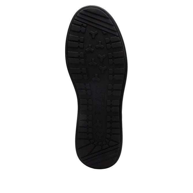 View of the bottom tread of a completely black shoe against a white background. 