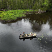 Two men in a brown fishing boat in a lake.