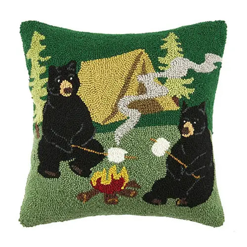 Green square pillow featuring a design with black bears roasting marshmallows over a fire against a white background. 