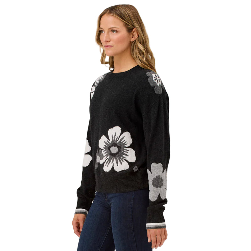Woman wearing a black sweater with floral patterns on a light gray background