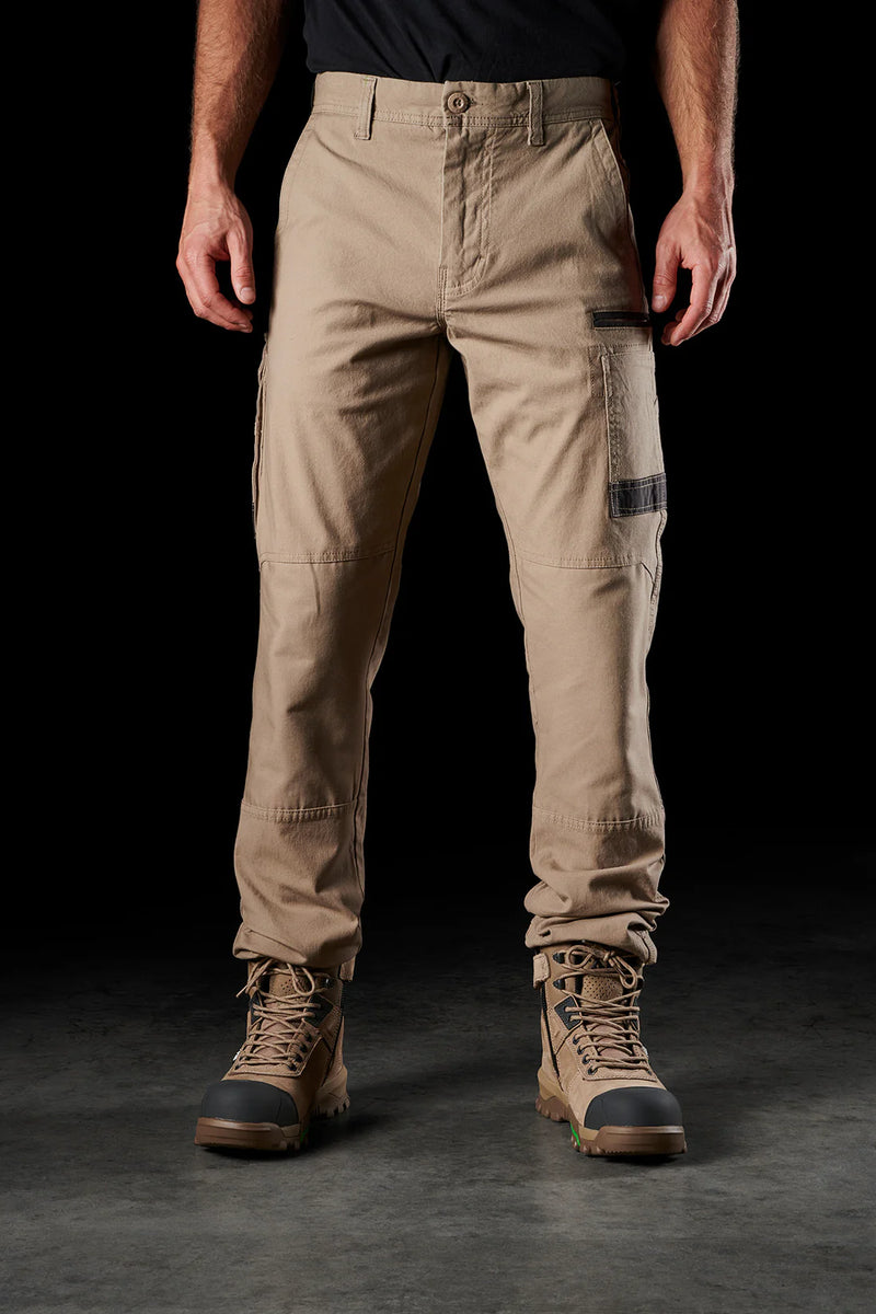 Person wearing tan pants and brown boots on a black background