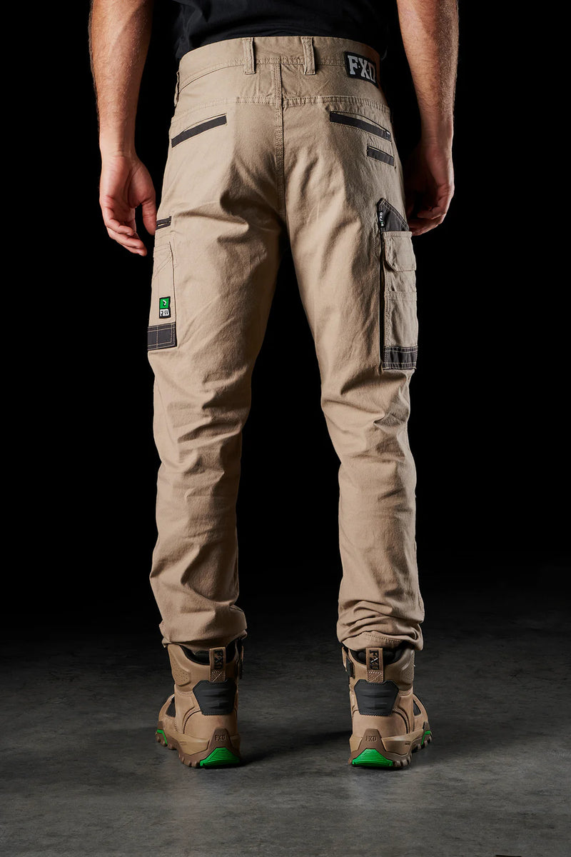 Person wearing beige cargo pants with visible branding on a black background