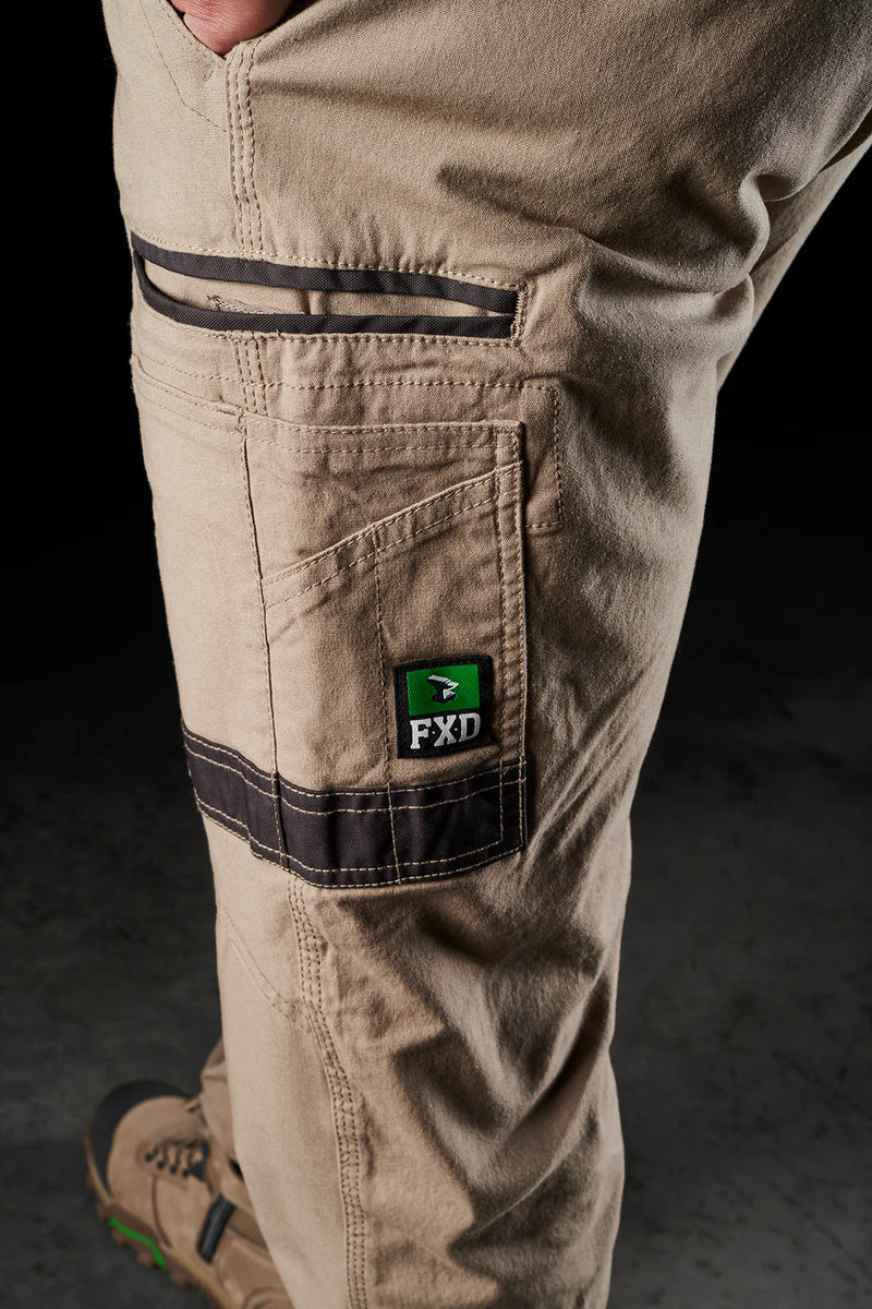 Close-up of beige pants with a brand logo on a dark background