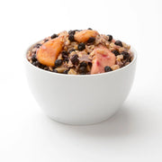 Picture of a white bowl filled to the brim with yummy looking oatmeal and fruit against a white background. 