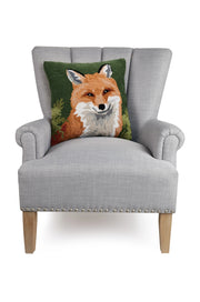 Pillow featuring a design of a fox resting on a gray chair against a white background. 