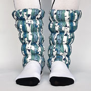 Front facing view of a model wearing white and blue gaiters against a white background. 