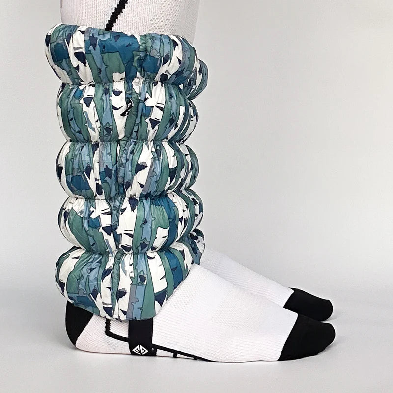 Side view of a model wearing white and blue gaiters against a white background. 