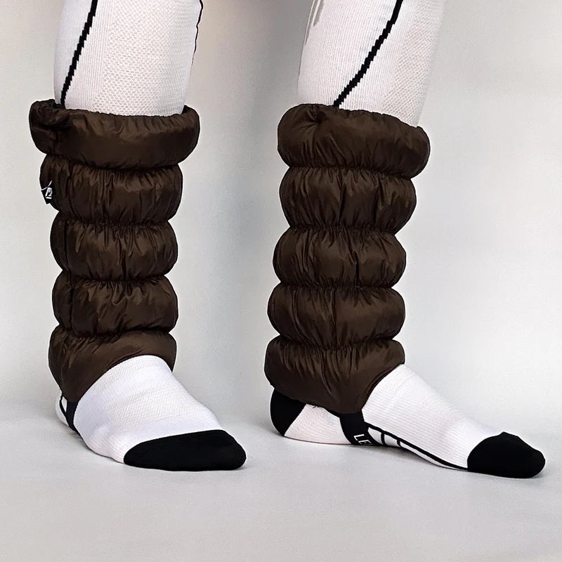 Side view of a model wearing brown gaiters against a white background. 