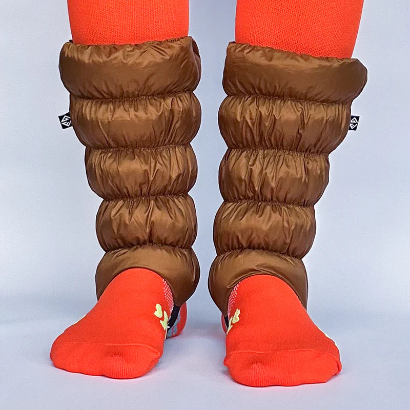 Front facing view of a model wearing orange socks and light brown gaiters over them against a white background. 