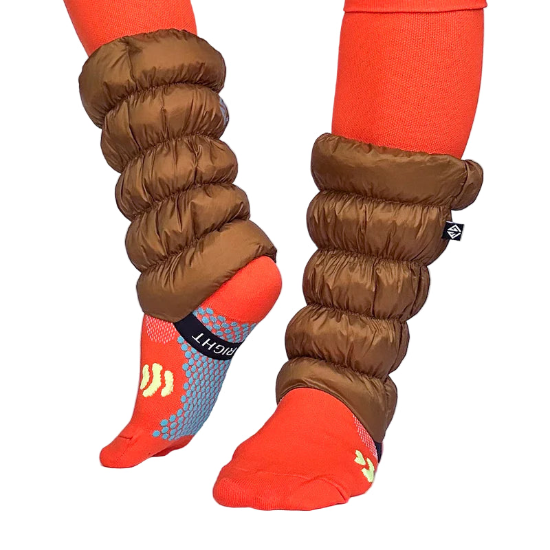 Front and side view of a model wearing light brown gaiters over orange socks against a white background. 