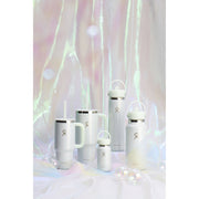 A set of white insulated water bottles and tumblers with silver metal accents and a small logo, arranged on a white surface with iridescent hanging fabric in the background.