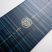 Close up of a black snowboard with blue and yellow accents against a white background. 