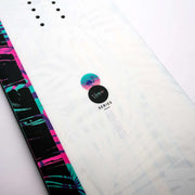 Close up of a white snowboard with black, blue, and pink accents against a white background. 