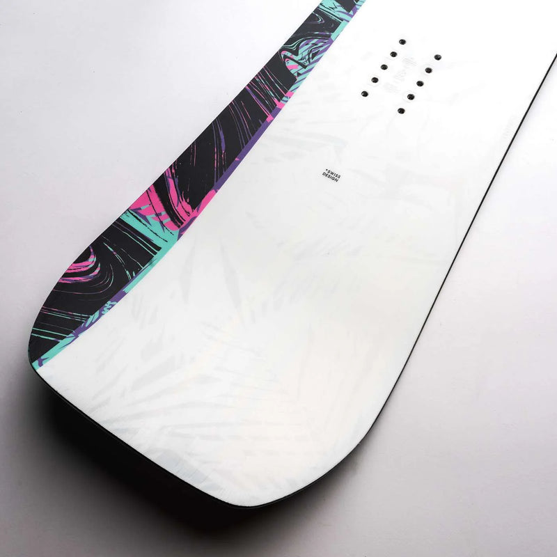 Close up of a white snowboard with black, blue, and pink accents against a gray background. 