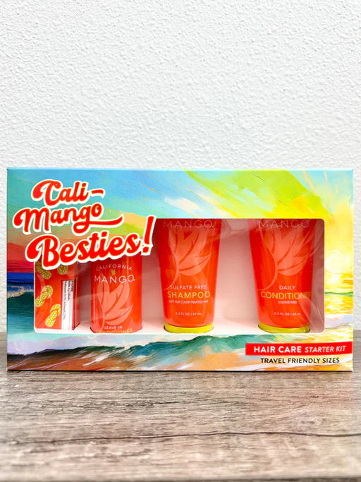 Cali-Mango Besties! Hair Care Starter Kit travel-friendly sizes, featuring a colorful tropical-themed box with three orange tubes of shampoo and conditioner and a small orange bottle, displayed on a wooden surface against a white wall.
