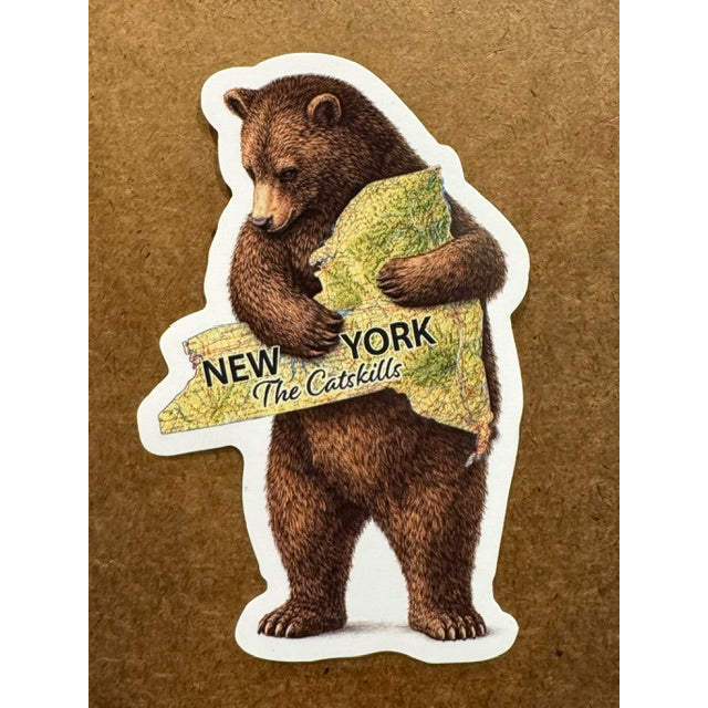 Sticker of a bear holding a New York shaped map on a wooden background.