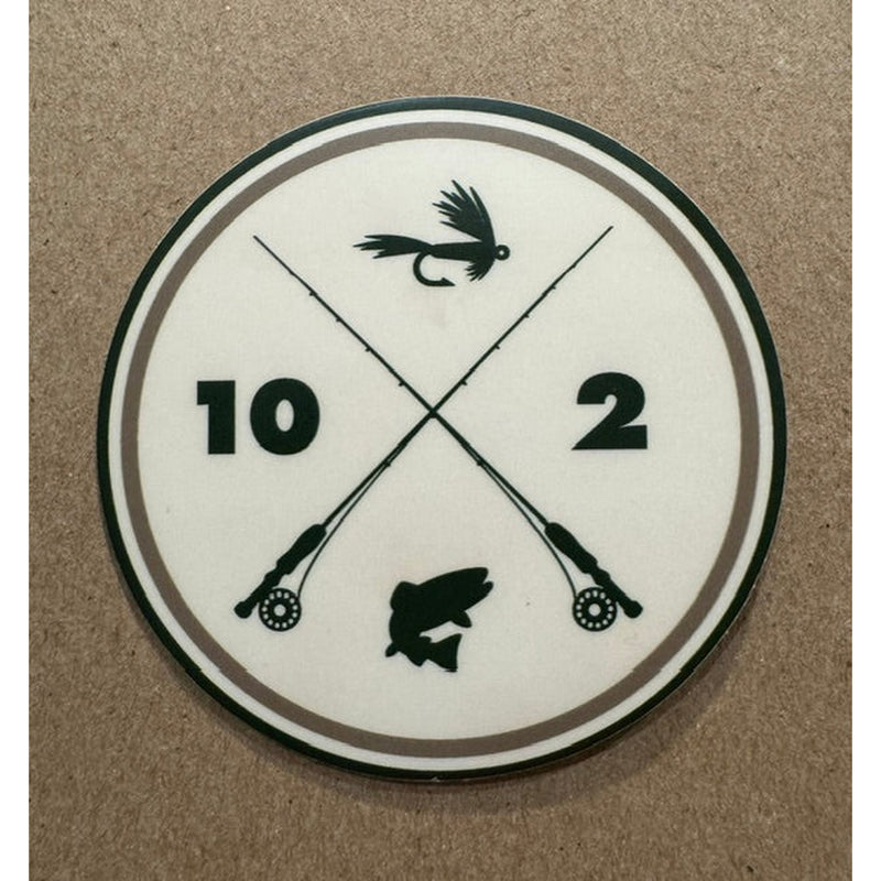 A circular white sticker featuring black crossed fishing rods, a fly lure, a fish silhouette, and the numbers 10 and 2
