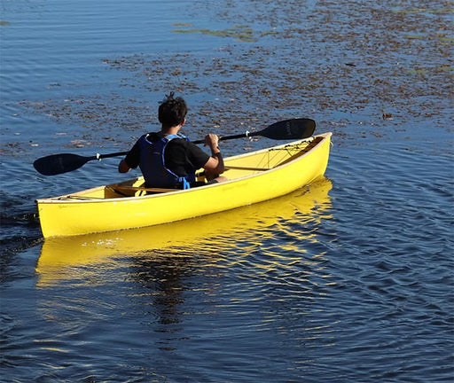 A man paddling a bright yellow canoe in a calm river.