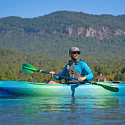 Man kayaking on a lake with mountains in the background