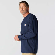 Side view of a man wearing a navy colored long sleeve shirt with a chest pocket against a white background. the chest pocket has a Carhartt logo on it. 