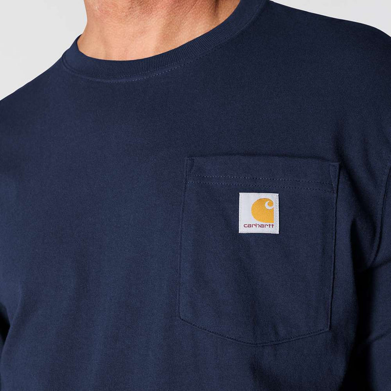 Close up of a man wearing a long sleeved navy colored shirt with a chest pocket and a Carhartt logo on it against a white background. 