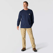 Man wearing a long sleeve navy colored shirt with a chest pocket against a white background. The chest pocket has a Carhartt logo on it. 