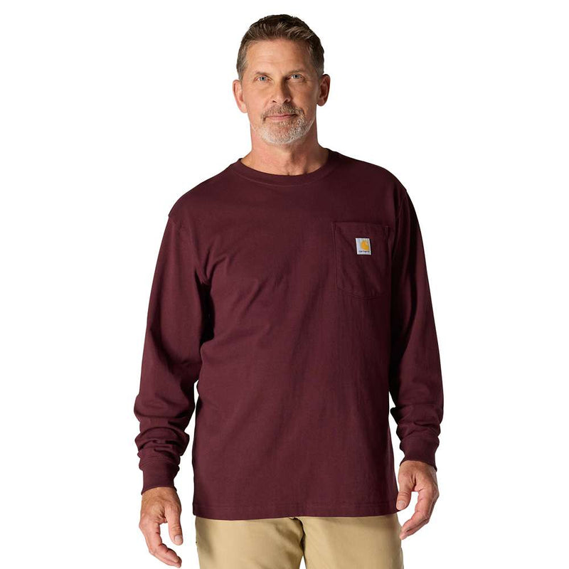 man wearing a maroon colored long sleeve shirt with a chest pocket against a white background. the chest pocket has a Carhartt logo on it. 