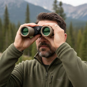 Man looking through green binoculars on a natural background.