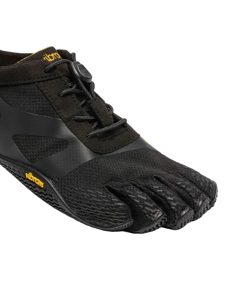 Side view of a black and yellow climbing shoe against a white background. 