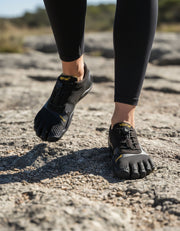 Woman wearing a pair of Vibram 5 Finger shoes on a rock.