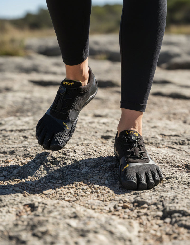 Woman wearing a pair of Vibram 5 Finger shoes on a rock.