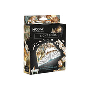 A boxed decorative light book titled 'Alice in Wonderland' by MODGY, shown upright on a plain white background. The packaging is predominantly black with illustrated artwork from the story, including Alice, the cat, and cards fanned out on the front.