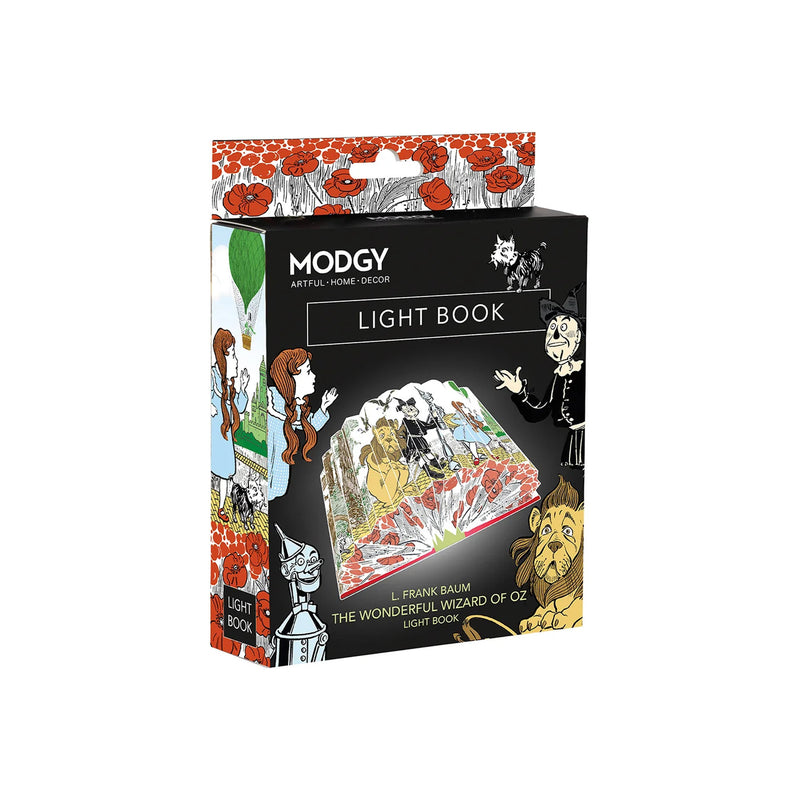 A boxed decorative light book by Modgy, shown in its retail packaging against a plain white background. The box is black with illustrated cover art featuring poppy borders, a cat, a wizard, and a lion, and the text 'MODGY ARTFUL HOME DECOR LIGHT BOOK' is visible.