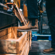 Person wearing brown work boots in a workshop setting