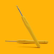 Two yellow crochet hooks with metal ends on a bright yellow background