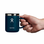 Hand holding a blue Hydro Flask mug on a white background