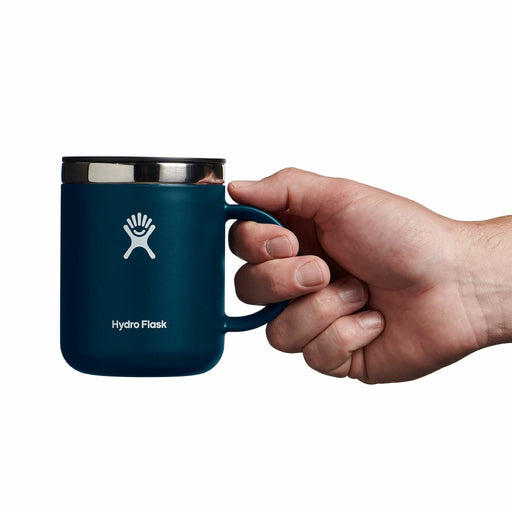 Hand holding a blue Hydro Flask mug on a white background