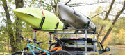 A lime green kayak as well as a white kayak strapped to a truck side by side. 