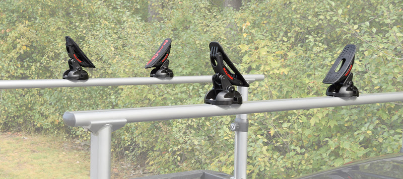 Four black and red kayak carriers with tie downs on the rack of a truck. 
